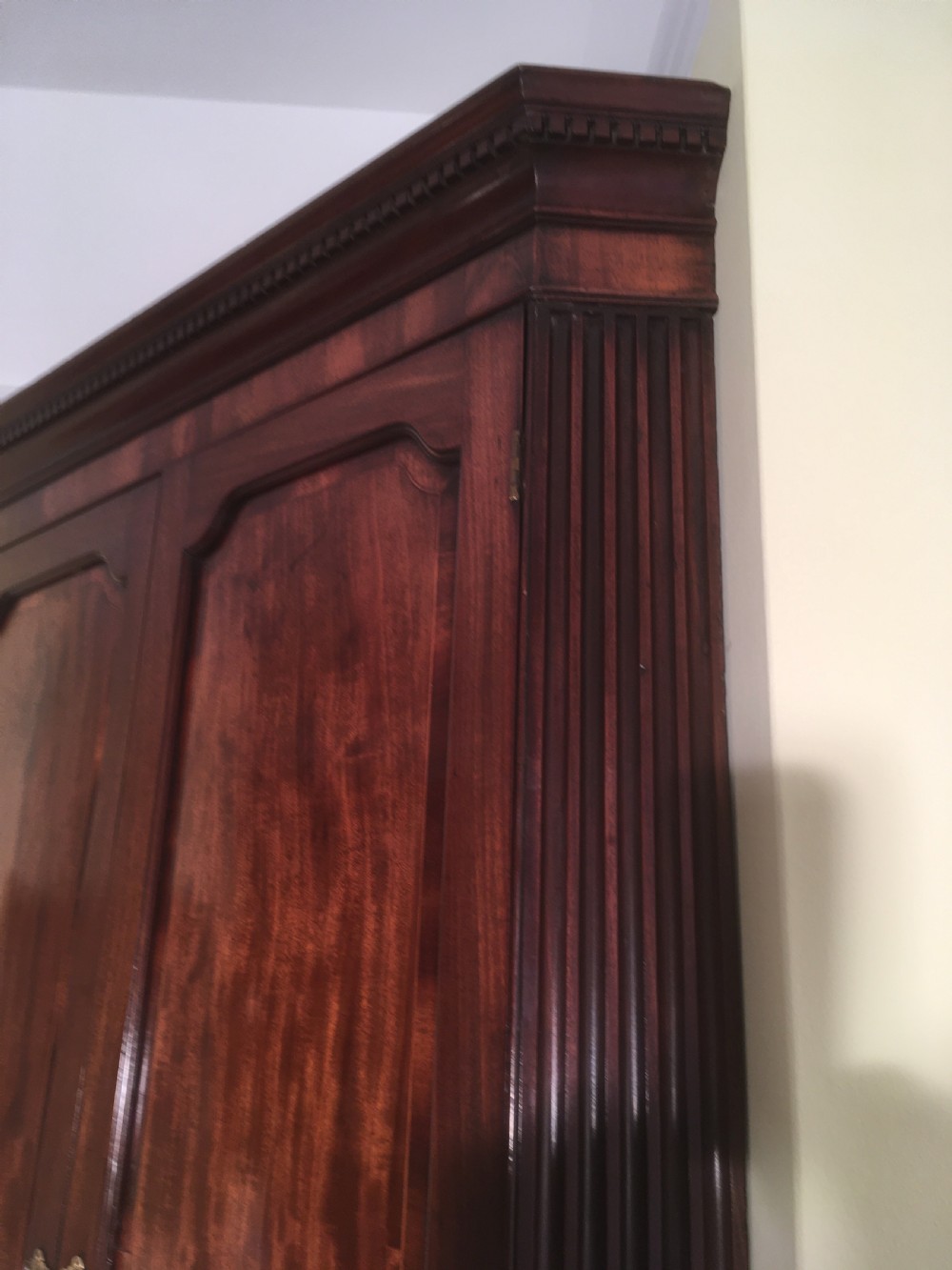 A wall-mounted Georgian mahogany corner cabinet featuring twin panelled doors, fluted side pilasters, and brass keyhole escutcheons. View IV