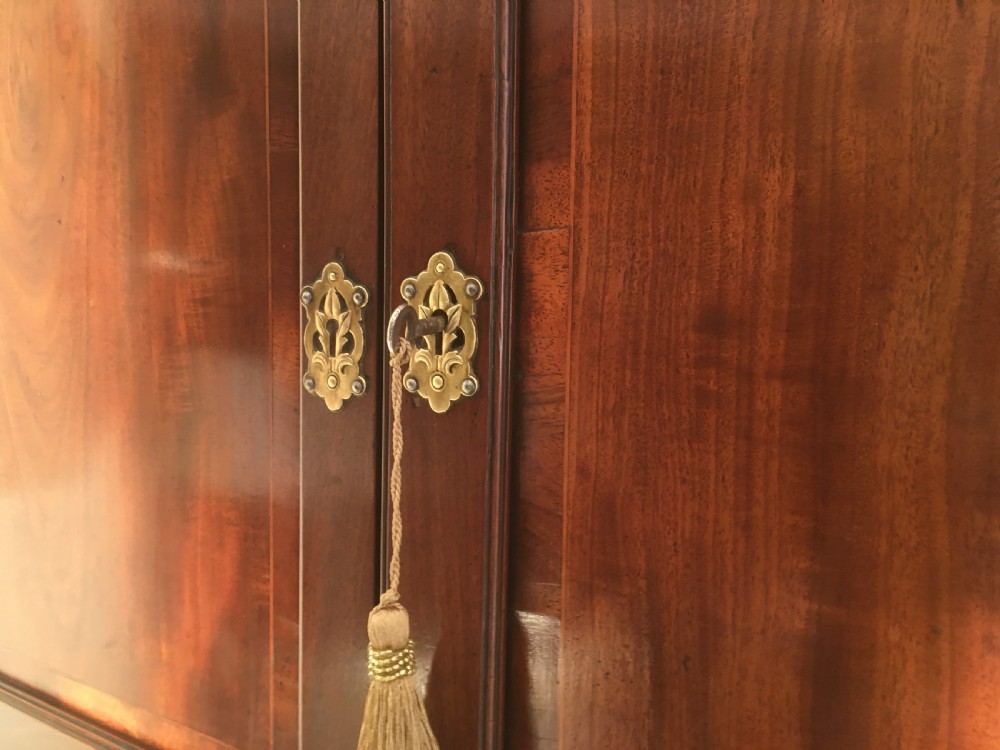 A wall-mounted Georgian mahogany corner cabinet featuring twin panelled doors, fluted side pilasters, and brass keyhole escutcheons. View VI