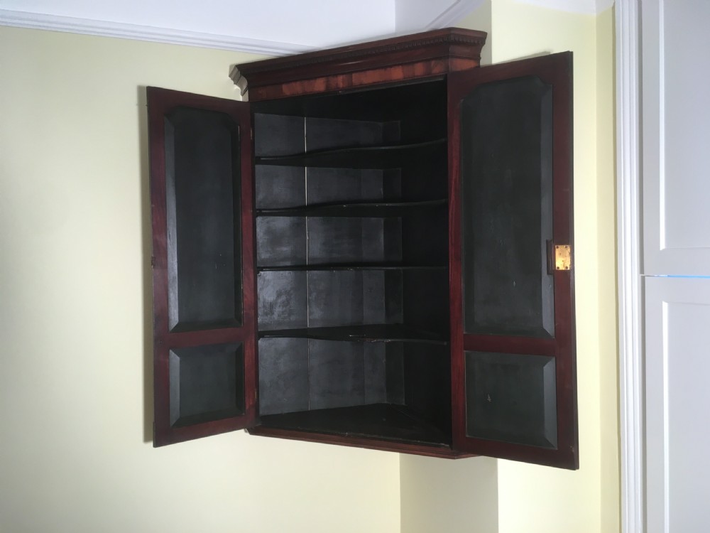 A wall-mounted Georgian mahogany corner cabinet featuring twin panelled doors, fluted side pilasters, and brass keyhole escutcheons. View VIII