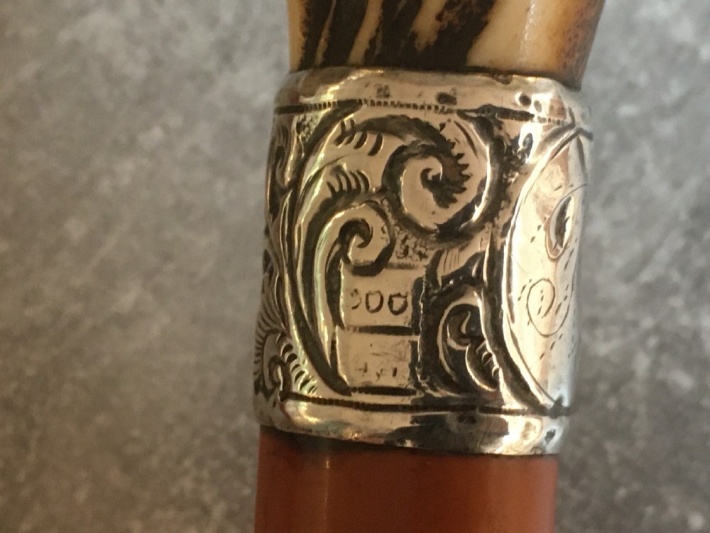An antique Malacca wood walking stick featuring a carved stag antler handle and silver collar, drawn to reveal a long steel concealed blade. View VI