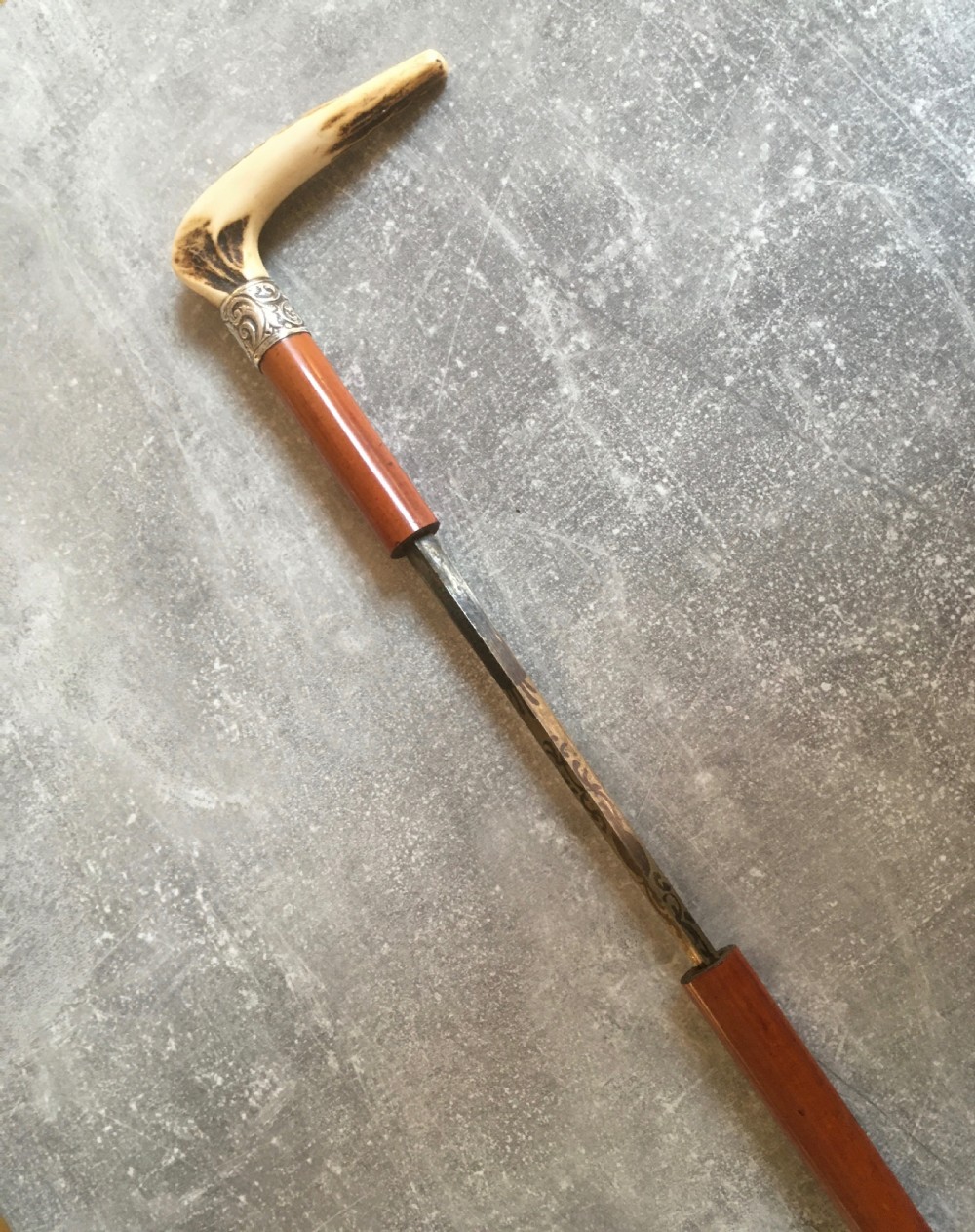 An antique Malacca wood walking stick featuring a carved stag antler handle and silver collar, drawn to reveal a long steel concealed blade. View XII