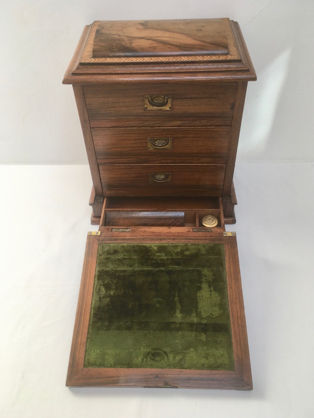 An inlaid walnut correspondence chest featuring geometric band inlay around figured wood panels, a domed lid, two front doors, and a central keyhole with a key inserted. View III