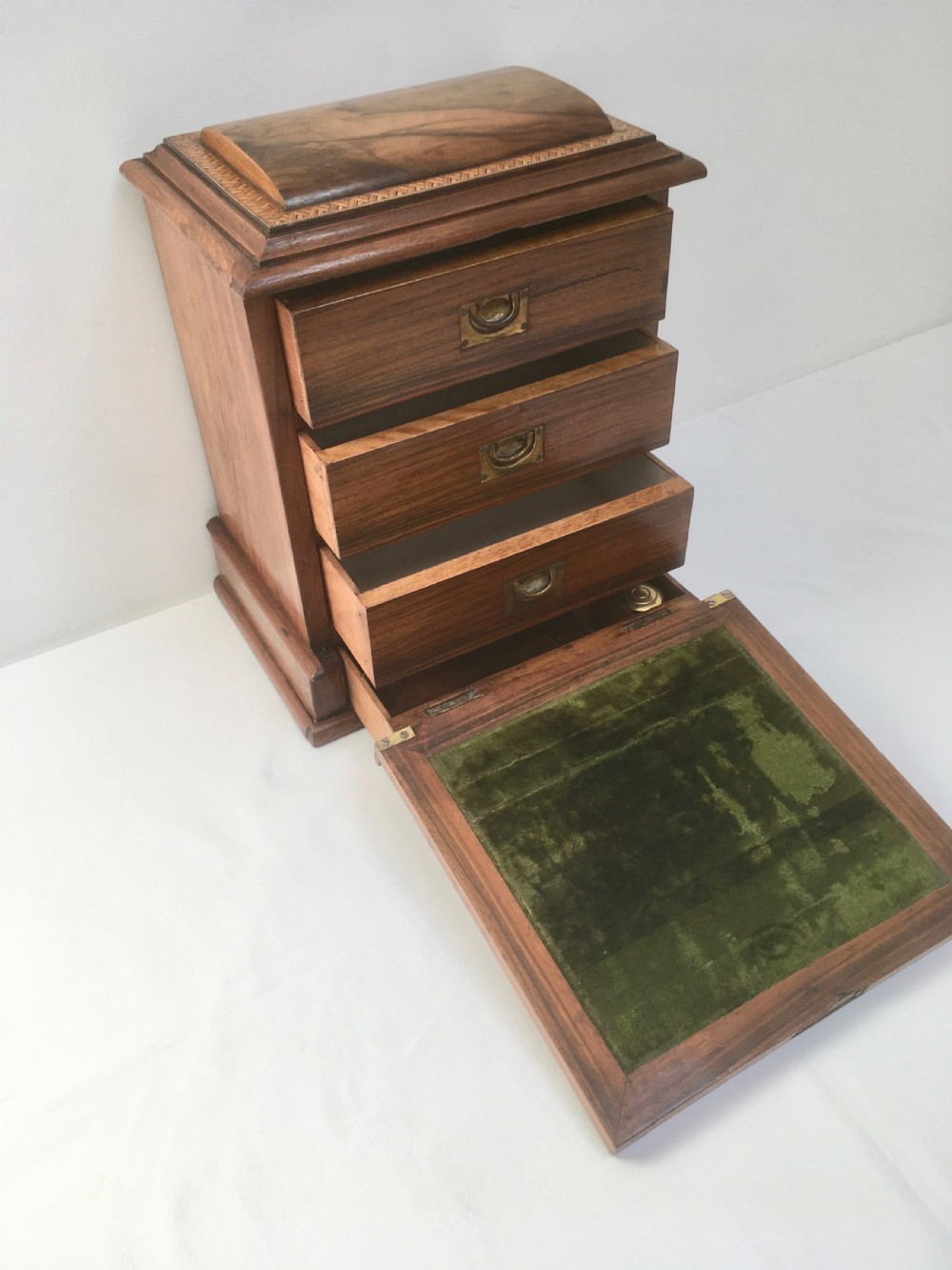 An inlaid walnut correspondence chest featuring geometric band inlay around figured wood panels, a domed lid, two front doors, and a central keyhole with a key inserted. View IV