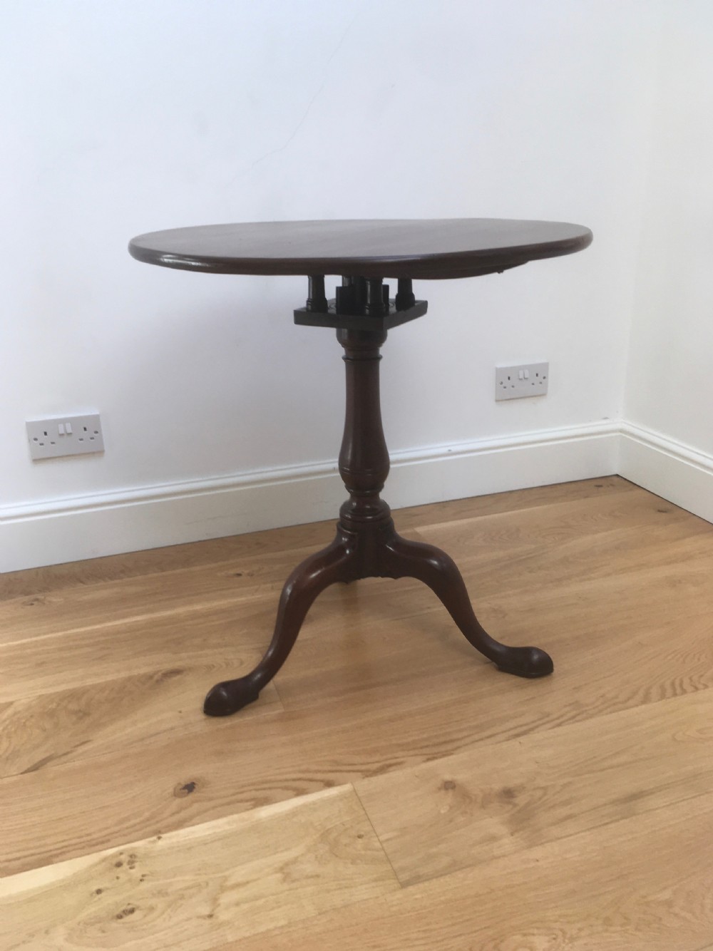 A Georgian mahogany tilt top table featuring a circular top, turned central pedestal, and tripod cabriole legs.