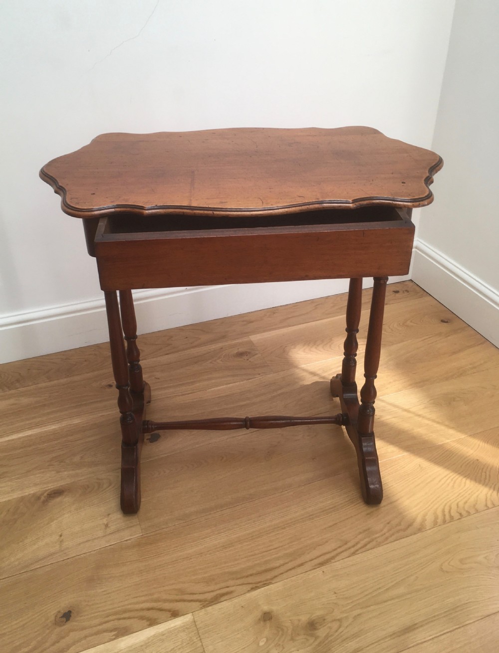 A Victorian mahogany side table featuring a serpentine top, turned legs with a stretcher base, and a single pull-out frieze drawer. View III