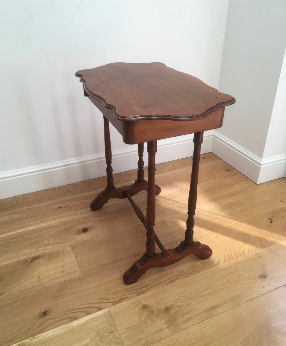 A Victorian mahogany side table featuring a serpentine top, turned legs with a stretcher base, and a single pull-out frieze drawer. View V
