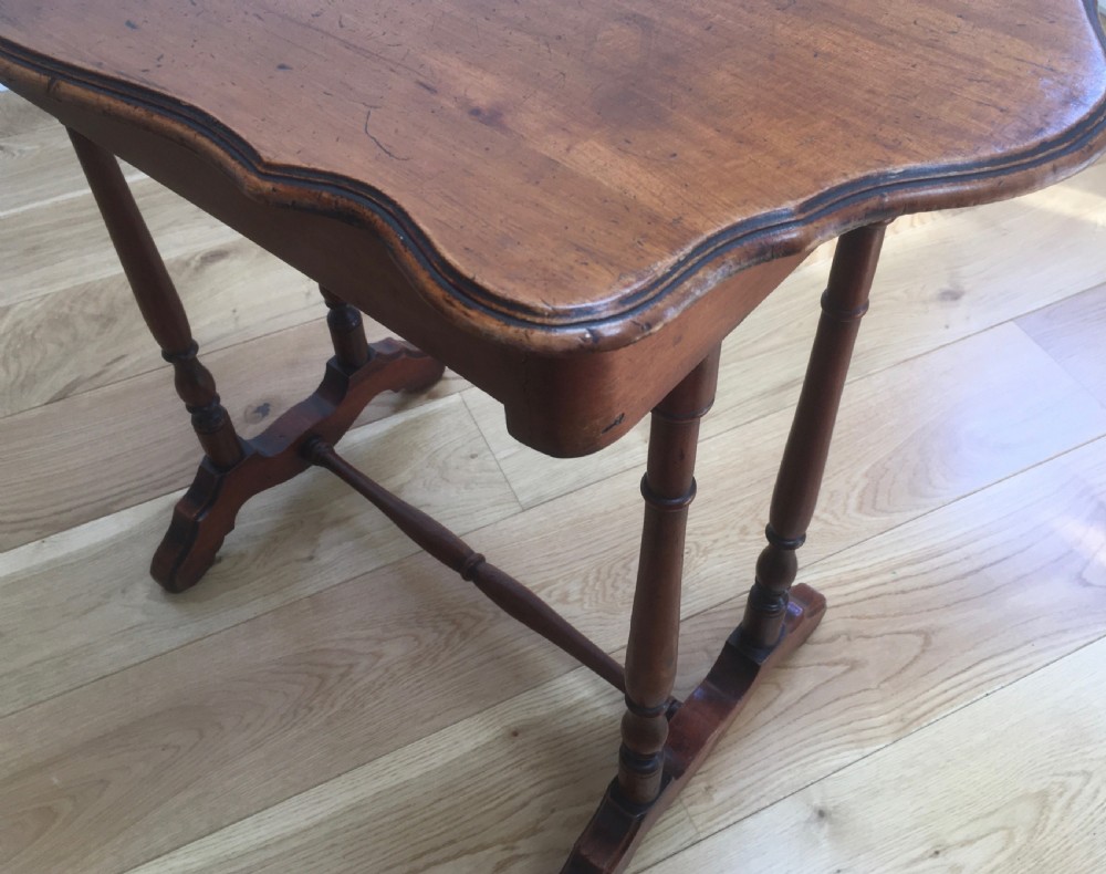 A Victorian mahogany side table featuring a serpentine top, turned legs with a stretcher base, and a single pull-out frieze drawer. View VIII