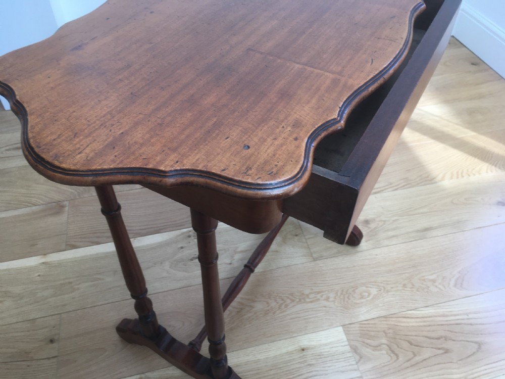 A Victorian mahogany side table featuring a serpentine top, turned legs with a stretcher base, and a single pull-out frieze drawer. View IX