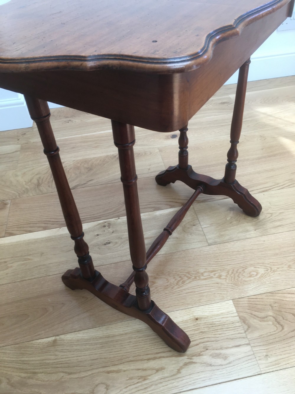 A Victorian mahogany side table featuring a serpentine top, turned legs with a stretcher base, and a single pull-out frieze drawer. View X