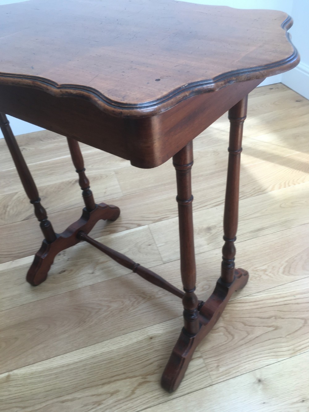 A Victorian mahogany side table featuring a serpentine top, turned legs with a stretcher base, and a single pull-out frieze drawer. View XI