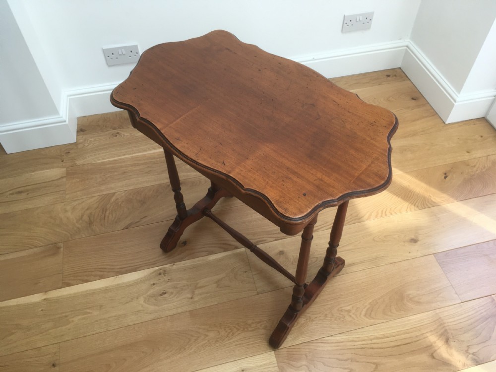 A Victorian mahogany side table featuring a serpentine top, turned legs with a stretcher base, and a single pull-out frieze drawer. View XII