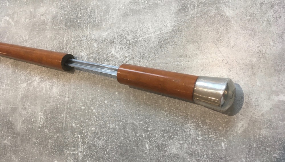 An antique Malacca cane walking stick featuring a smooth turned wood shaft, a brass ferrule at the tip, and a silver cap handle. View VIII