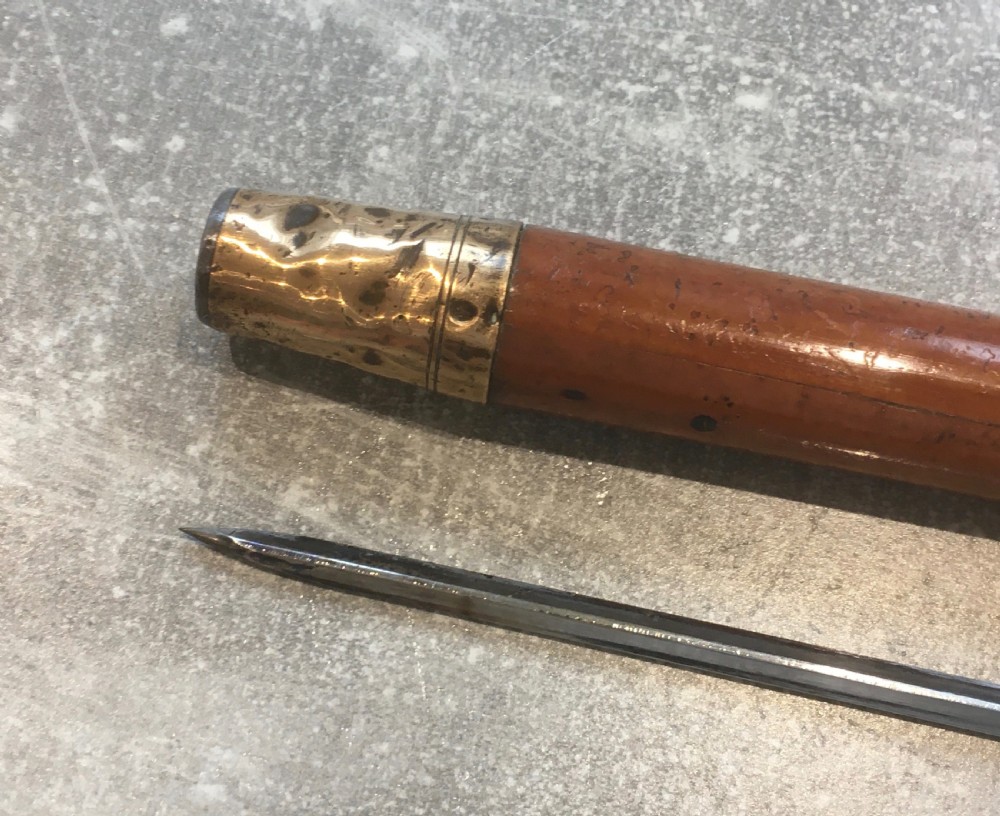 An antique Malacca cane walking stick featuring a smooth turned wood shaft, a brass ferrule at the tip, and a silver cap handle. View IX