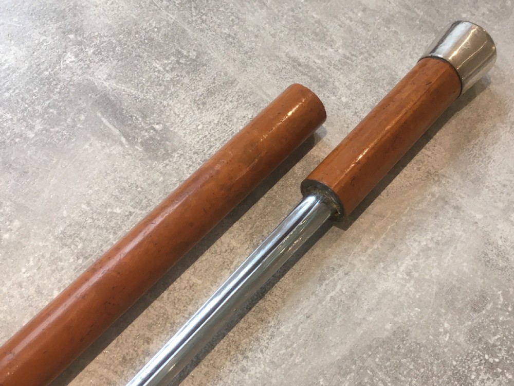 An antique Malacca cane walking stick featuring a smooth turned wood shaft, a brass ferrule at the tip, and a silver cap handle. View X