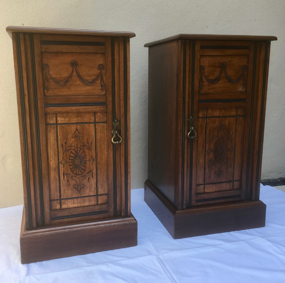 A matching pair of slim Edwardian mahogany bedside cabinets featuring carved swag decoration, single cupboards, brass handles, and solid plinth bases. View VII