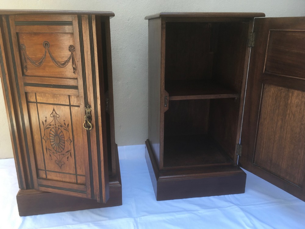 A matching pair of slim Edwardian mahogany bedside cabinets featuring carved swag decoration, single cupboards, brass handles, and solid plinth bases. View XI