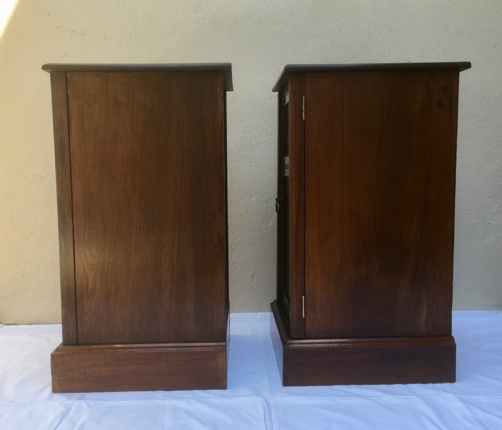 A matching pair of slim Edwardian mahogany bedside cabinets featuring carved swag decoration, single cupboards, brass handles, and solid plinth bases. View XIII