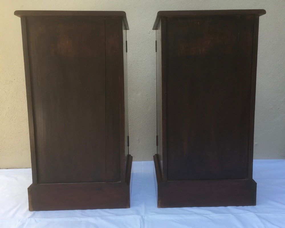 A matching pair of slim Edwardian mahogany bedside cabinets featuring carved swag decoration, single cupboards, brass handles, and solid plinth bases. View XIV