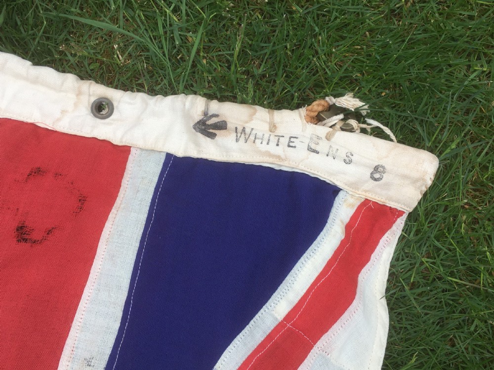 A rectangular Second World War Royal Navy White Ensign flag featuring a white field with a red Saint Georges Cross, a Union Jack canton, and a stitched canvas edge with rope lanyard. View II