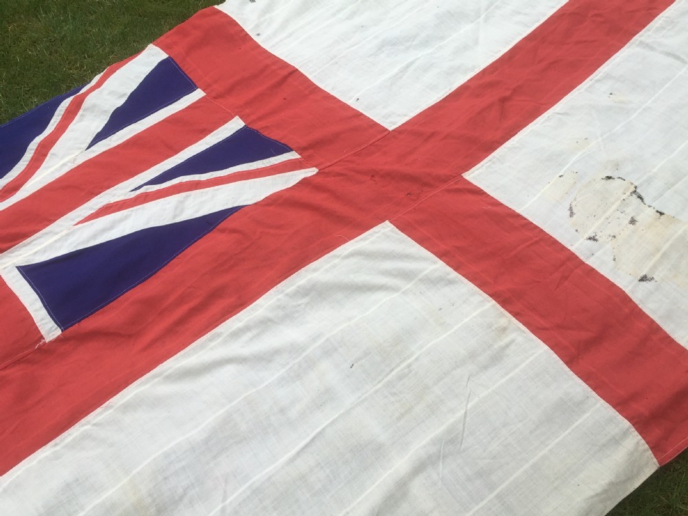 A rectangular Second World War Royal Navy White Ensign flag featuring a white field with a red Saint Georges Cross, a Union Jack canton, and a stitched canvas edge with rope lanyard. View IV