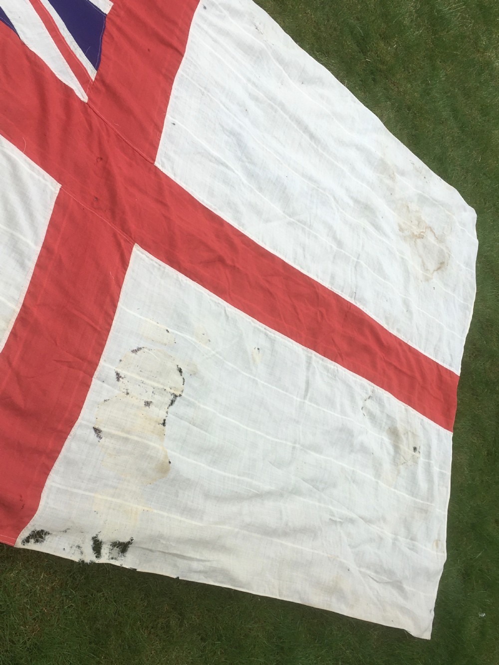 A rectangular Second World War Royal Navy White Ensign flag featuring a white field with a red Saint Georges Cross, a Union Jack canton, and a stitched canvas edge with rope lanyard. View VI