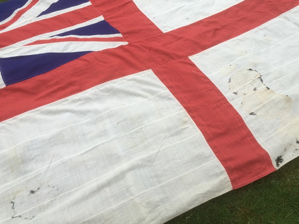 A rectangular Second World War Royal Navy White Ensign flag featuring a white field with a red Saint Georges Cross, a Union Jack canton, and a stitched canvas edge with rope lanyard. View VII