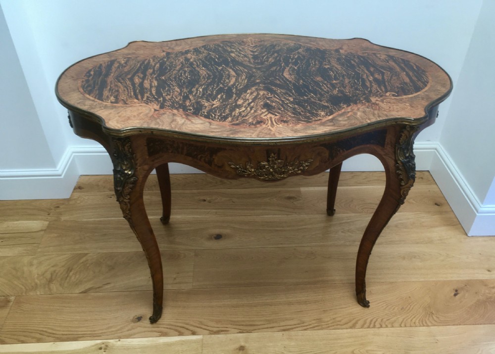 A Louis XV style shaped centre table featuring inlaid coromandel timber, curved cabriole legs, and gilded bronze mounts.