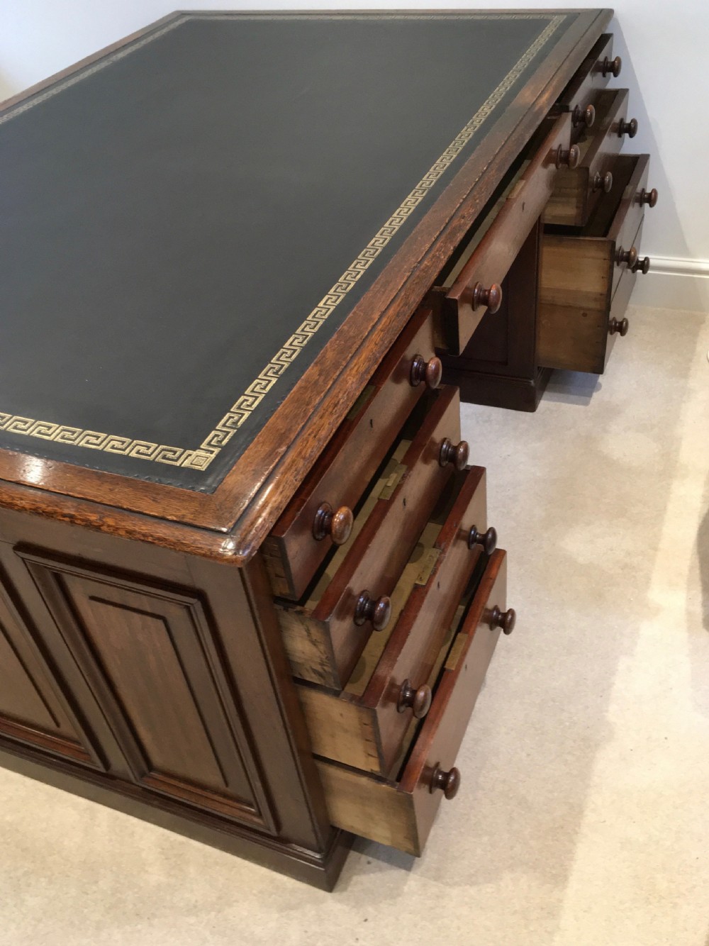 A large mahogany partners desk featuring a dark green gold-tooled leather writing surface and twin pedestals with turned knob handles. View V