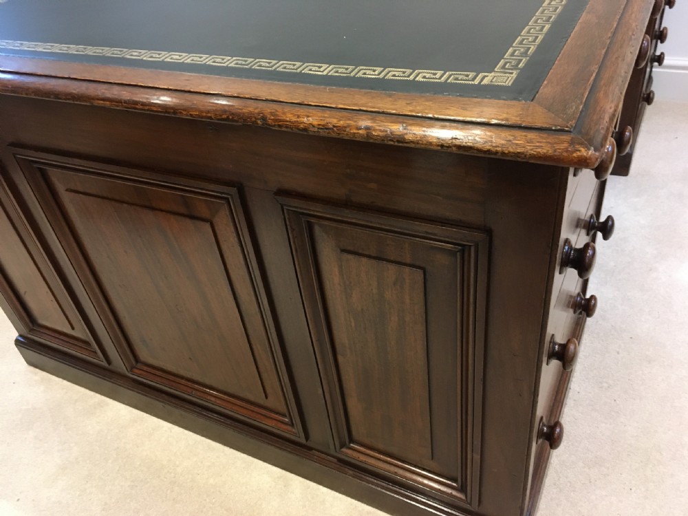 A large mahogany partners desk featuring a dark green gold-tooled leather writing surface and twin pedestals with turned knob handles. View XIII