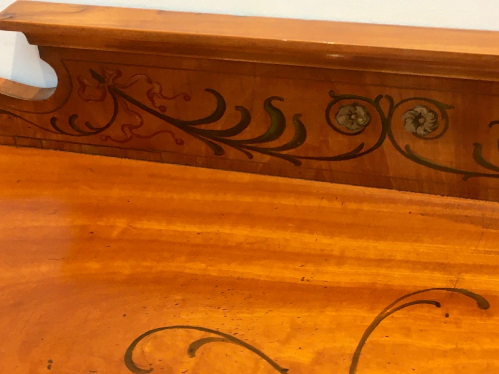 A satinwood side cabinet featuring a serpentine front, twin cupboard doors decorated with hand-painted Neoclassical urns and floral swags, supported by tapered legs. View XI