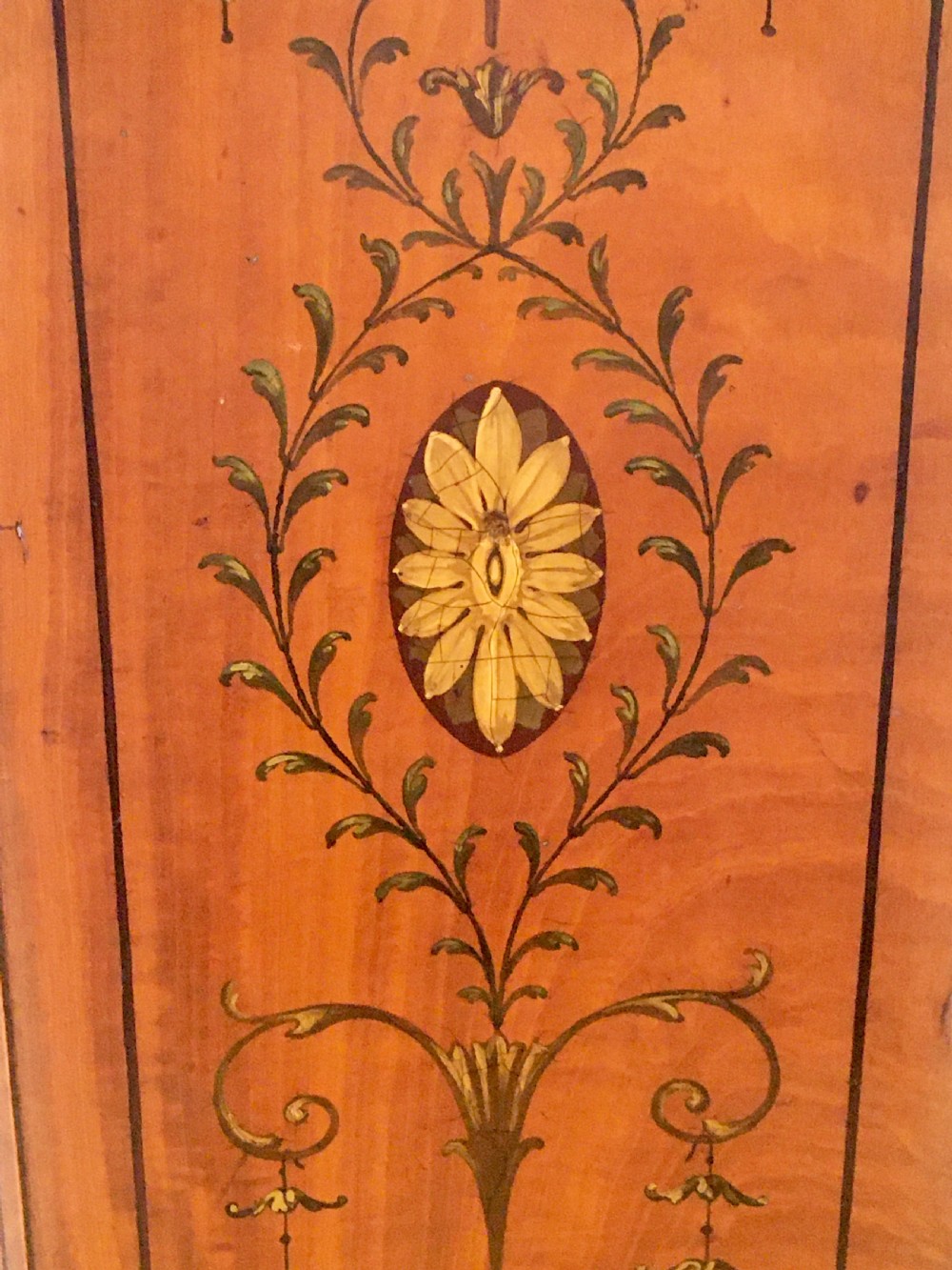 A satinwood side cabinet featuring a serpentine front, twin cupboard doors decorated with hand-painted Neoclassical urns and floral swags, supported by tapered legs. View XIII