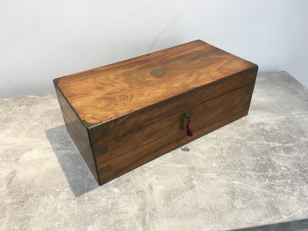 A rectangular Georgian walnut writing slope featuring brass corner brackets, a central round brass medallion, and a front key escutcheon with a red tassel. View II