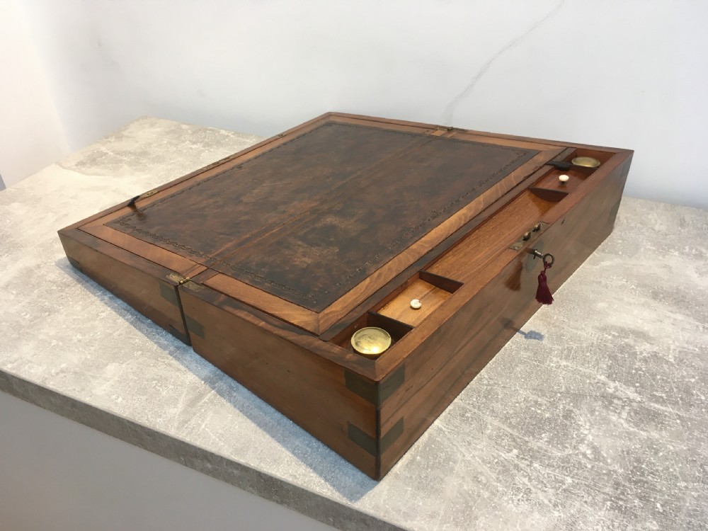 A rectangular Georgian walnut writing slope featuring brass corner brackets, a central round brass medallion, and a front key escutcheon with a red tassel. View III