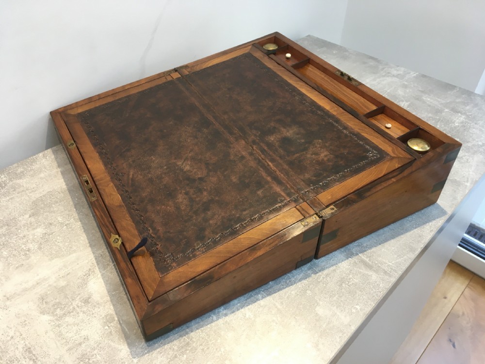 A rectangular Georgian walnut writing slope featuring brass corner brackets, a central round brass medallion, and a front key escutcheon with a red tassel. View IV