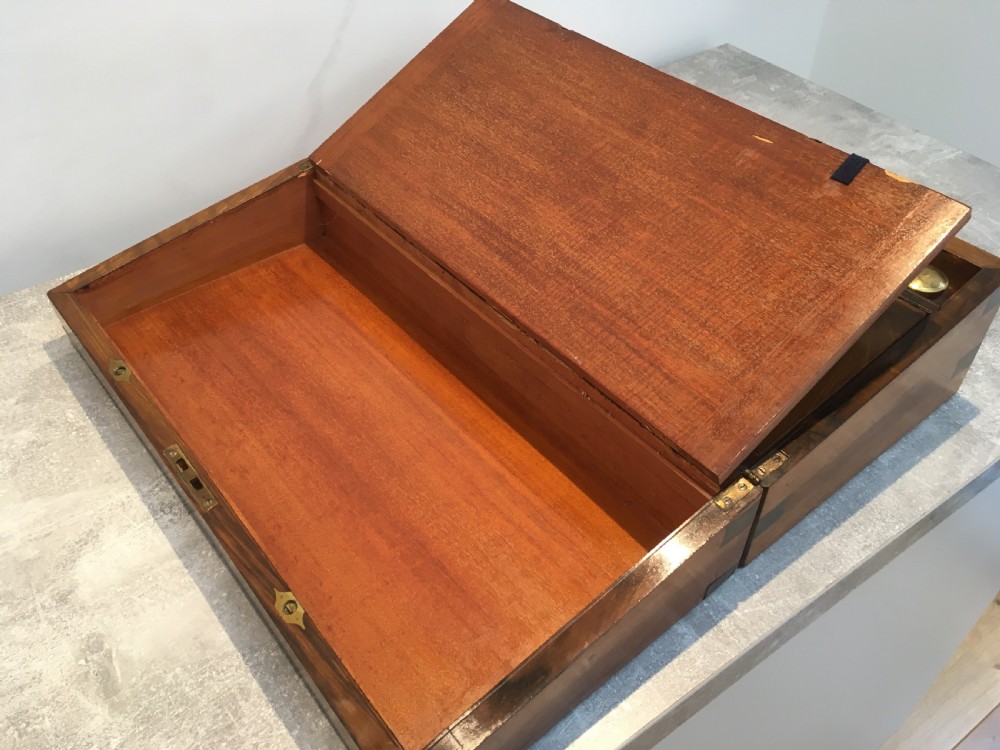 A rectangular Georgian walnut writing slope featuring brass corner brackets, a central round brass medallion, and a front key escutcheon with a red tassel. View VII
