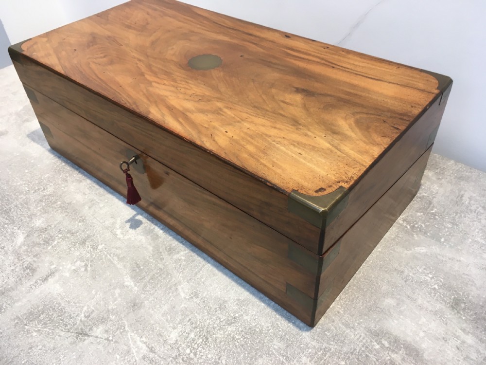 A rectangular Georgian walnut writing slope featuring brass corner brackets, a central round brass medallion, and a front key escutcheon with a red tassel. View XIII