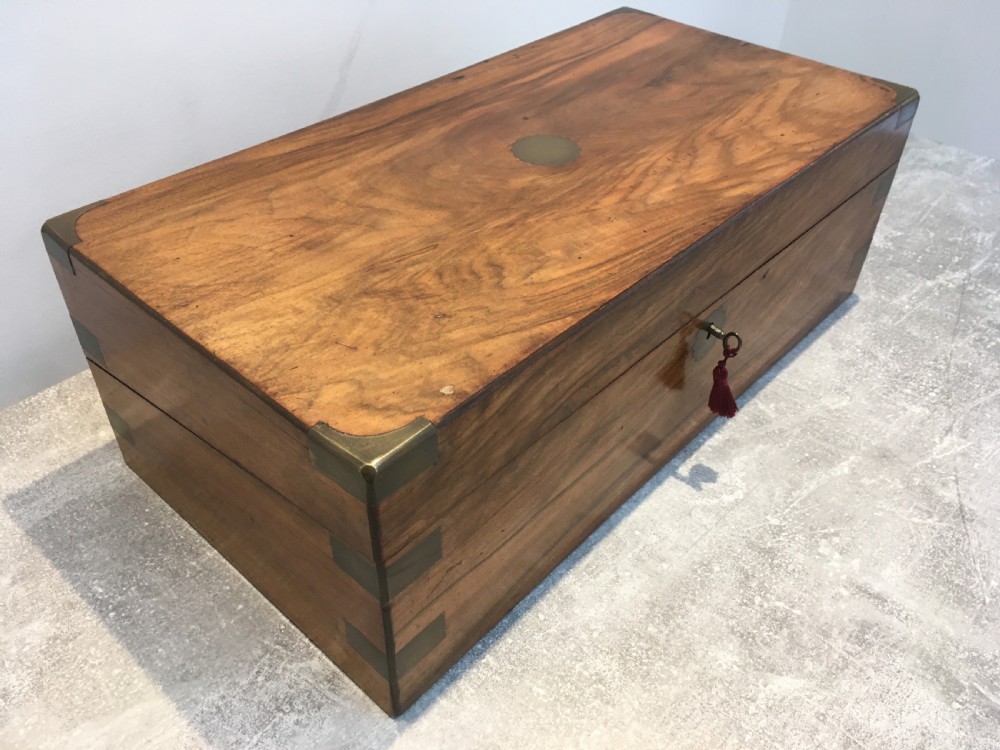 A rectangular Georgian walnut writing slope featuring brass corner brackets, a central round brass medallion, and a front key escutcheon with a red tassel. View XIV
