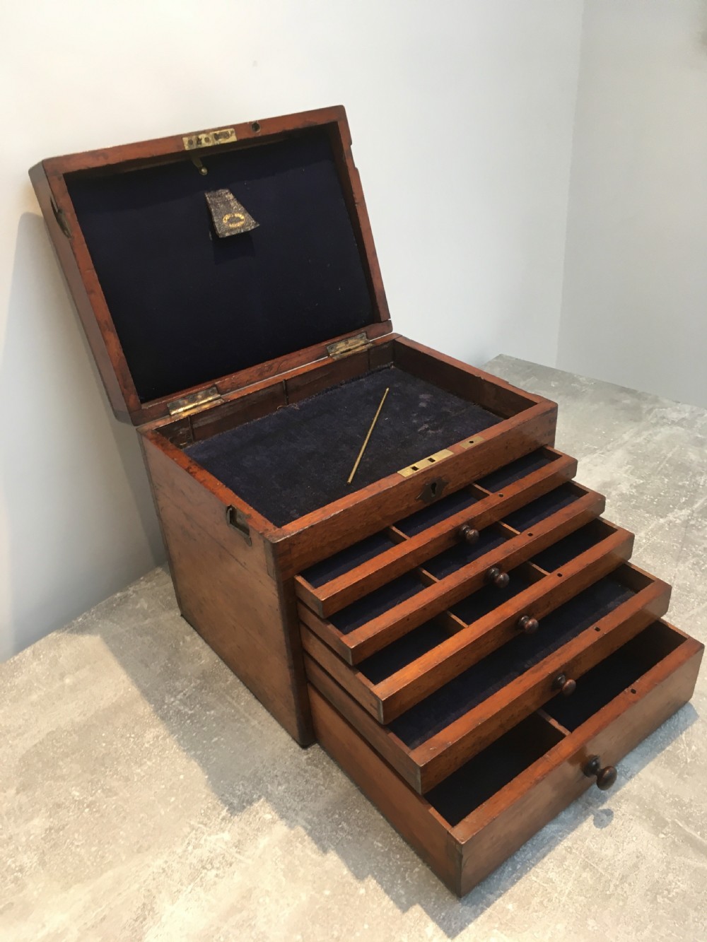 A Victorian mahogany instrument chest featuring a hinged top lid and five graduated drawers lined with dark blue velvet.