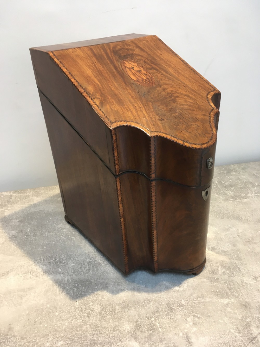 A George III mahogany slanted-top knife box shown open, featuring slotted interior fittings, string inlay, and a star marquetry motif on the inside lid. View II