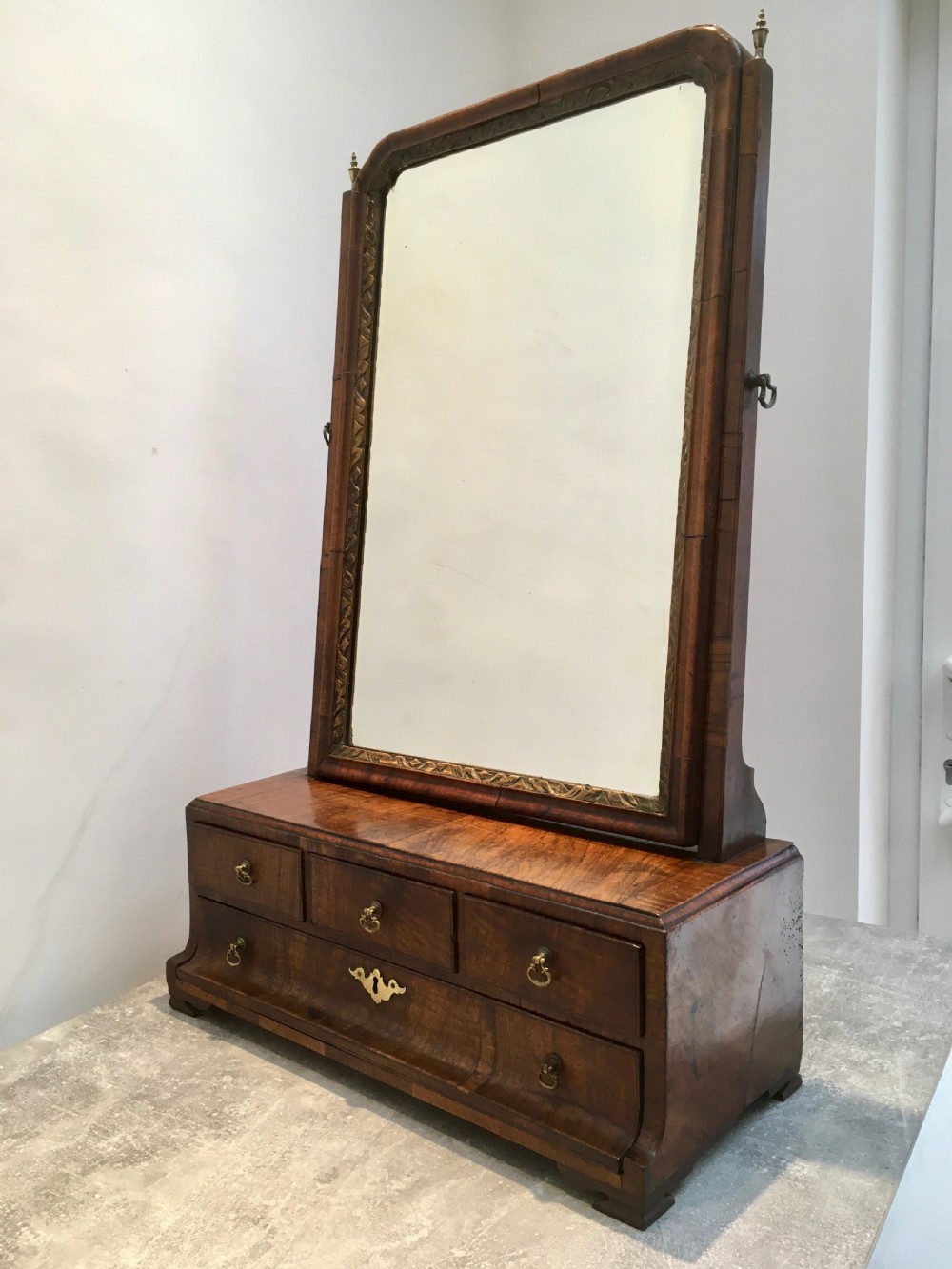An 18th-century walnut toilet mirror featuring an adjustable rectangular glass frame set above a stepped base with small drawers and brass drop handles. View II