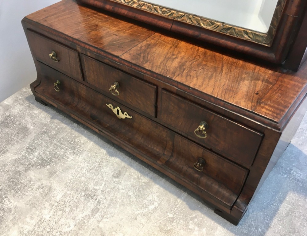 An 18th-century walnut toilet mirror featuring an adjustable rectangular glass frame set above a stepped base with small drawers and brass drop handles. View IV