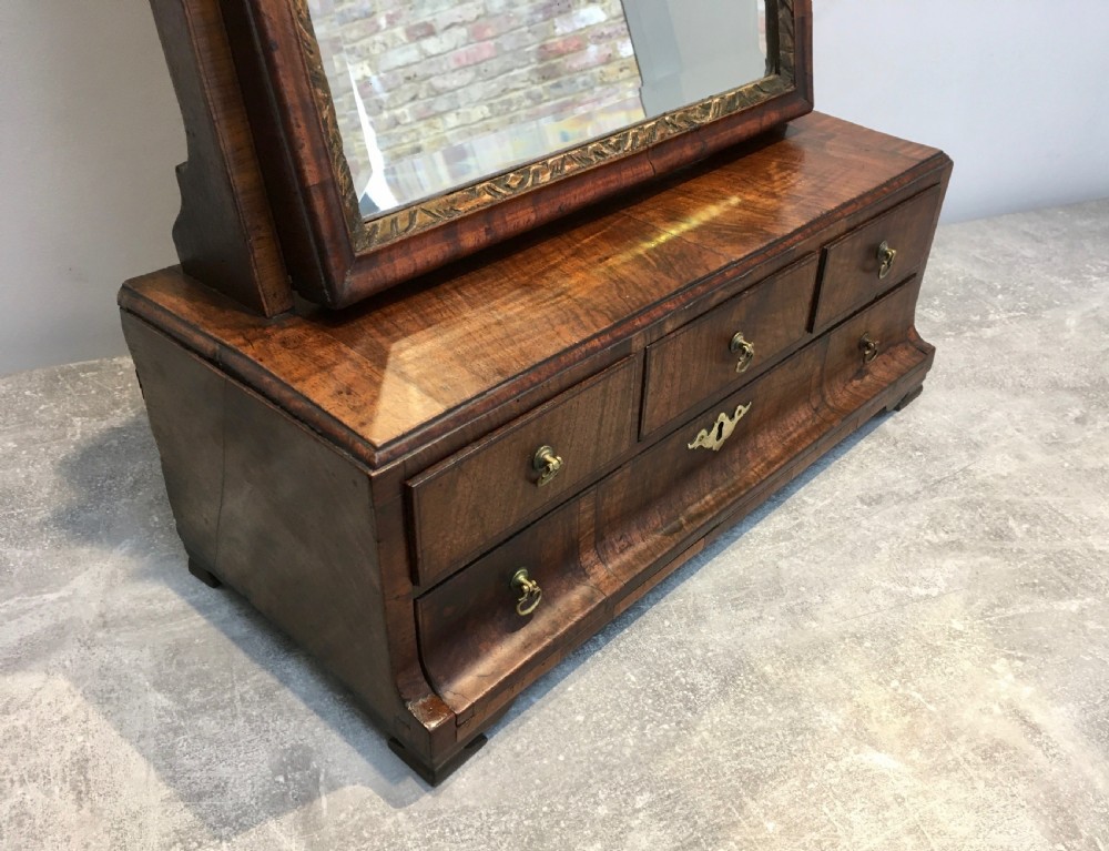 An 18th-century walnut toilet mirror featuring an adjustable rectangular glass frame set above a stepped base with small drawers and brass drop handles. View V