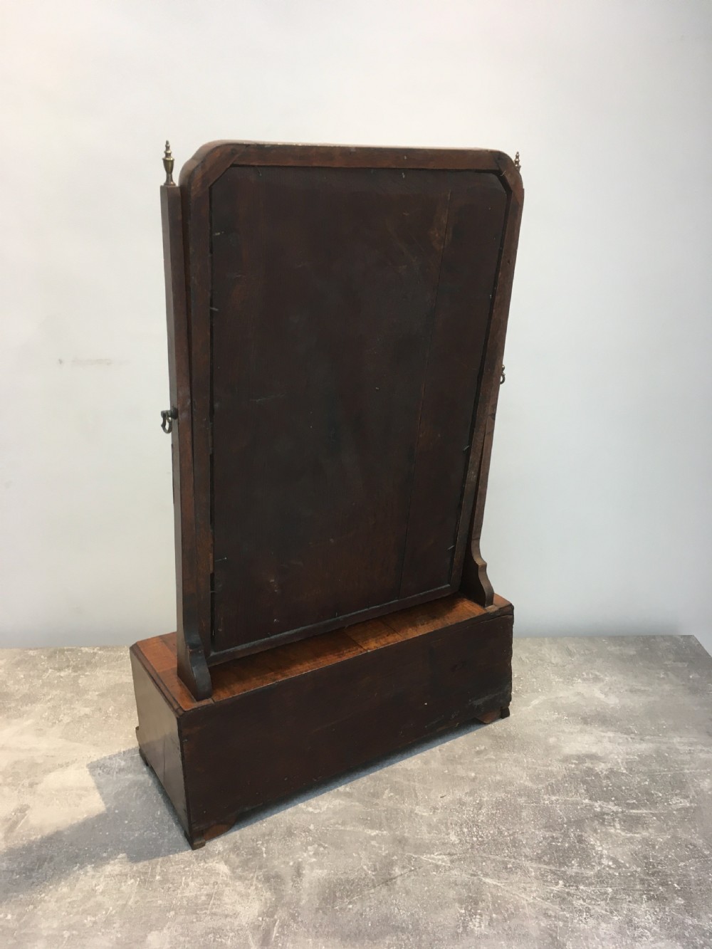 An 18th-century walnut toilet mirror featuring an adjustable rectangular glass frame set above a stepped base with small drawers and brass drop handles. View XII