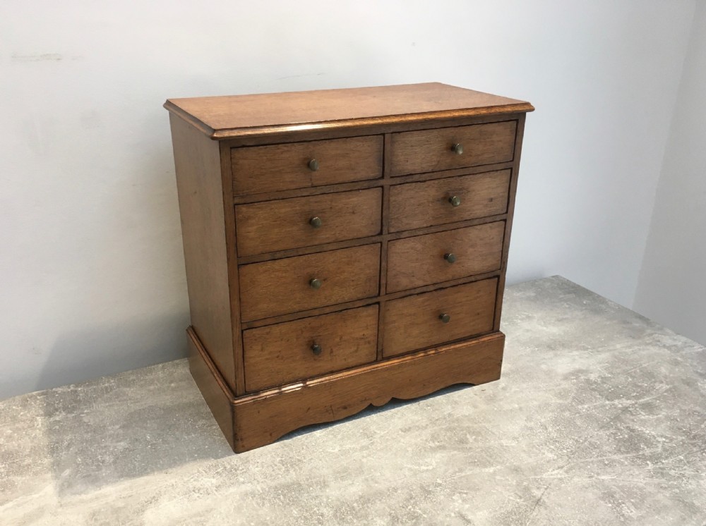 A nineteenth-century medium brown oak collectors chest featuring eight small drawers arranged in two columns with round metal knobs.