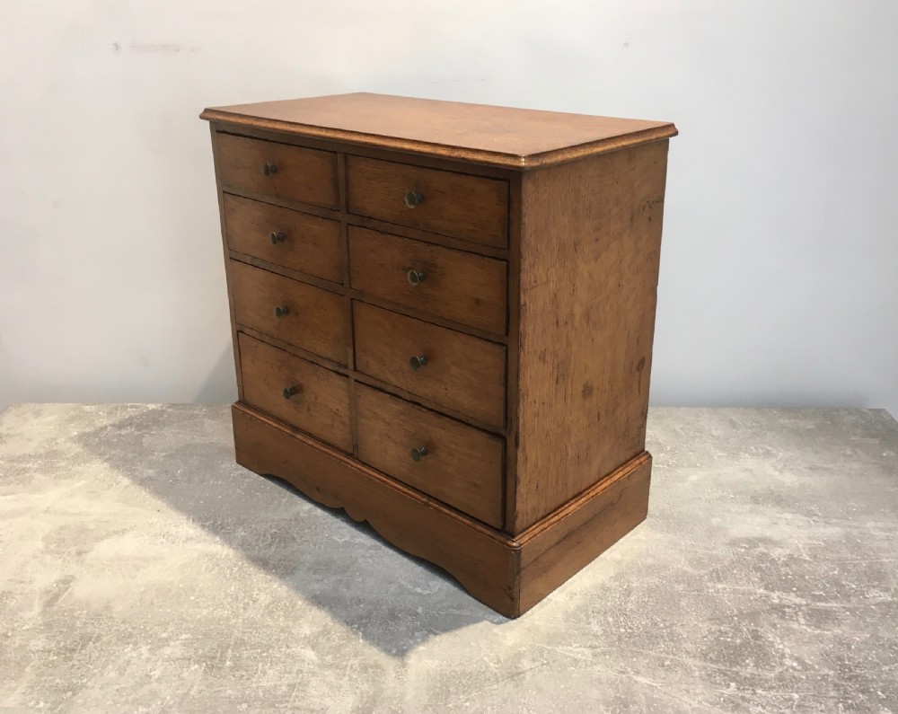 A nineteenth-century medium brown oak collectors chest featuring eight small drawers arranged in two columns with round metal knobs. View X