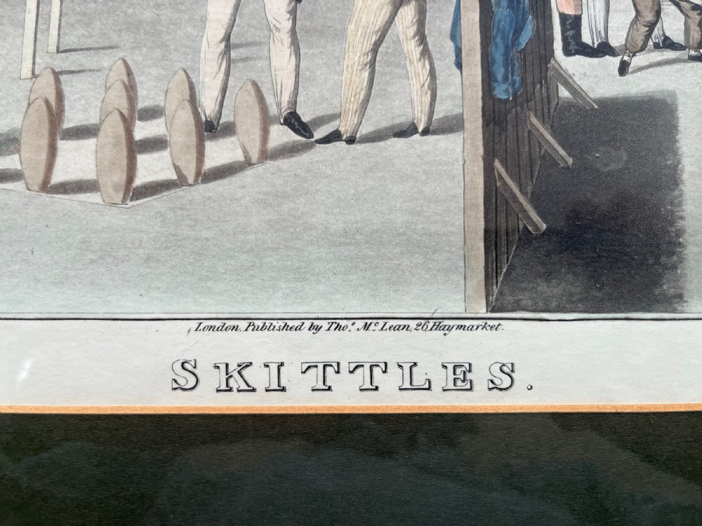 A framed antique hand-coloured engraving depicting gentlemen playing skittles outside an English pub, set within a dark green mount and a warm wood frame. View III