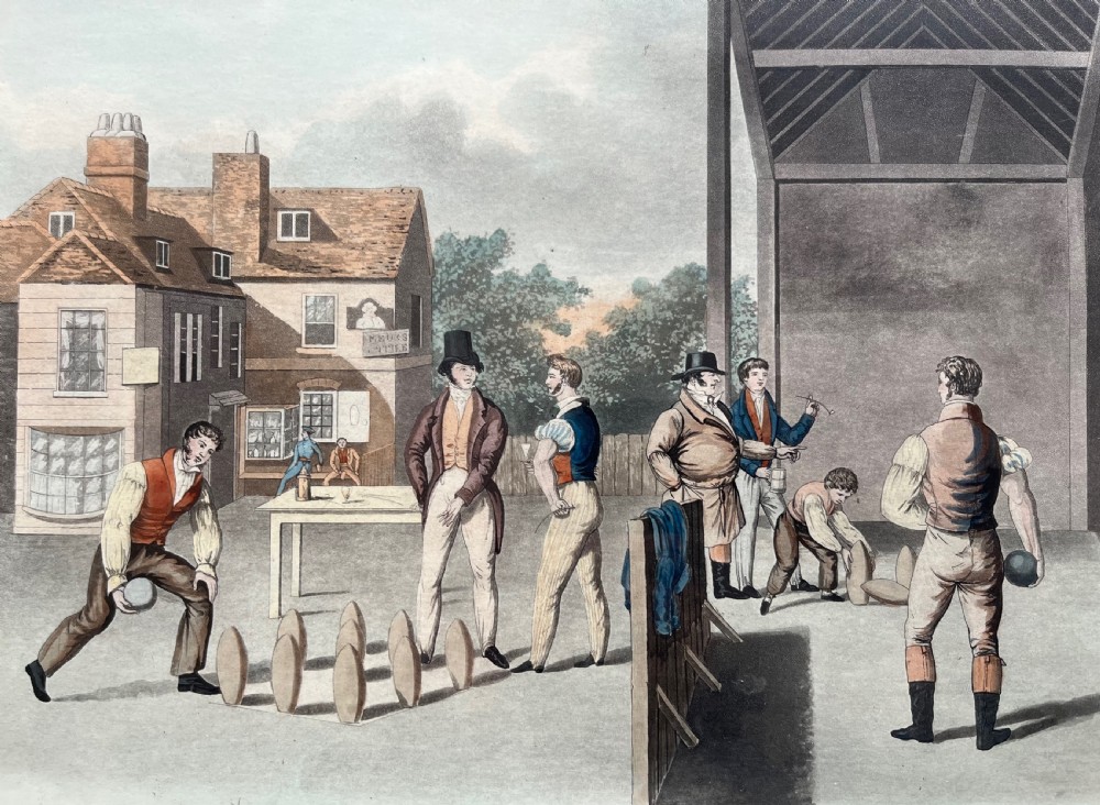 A framed antique hand-coloured engraving depicting gentlemen playing skittles outside an English pub, set within a dark green mount and a warm wood frame. View VI