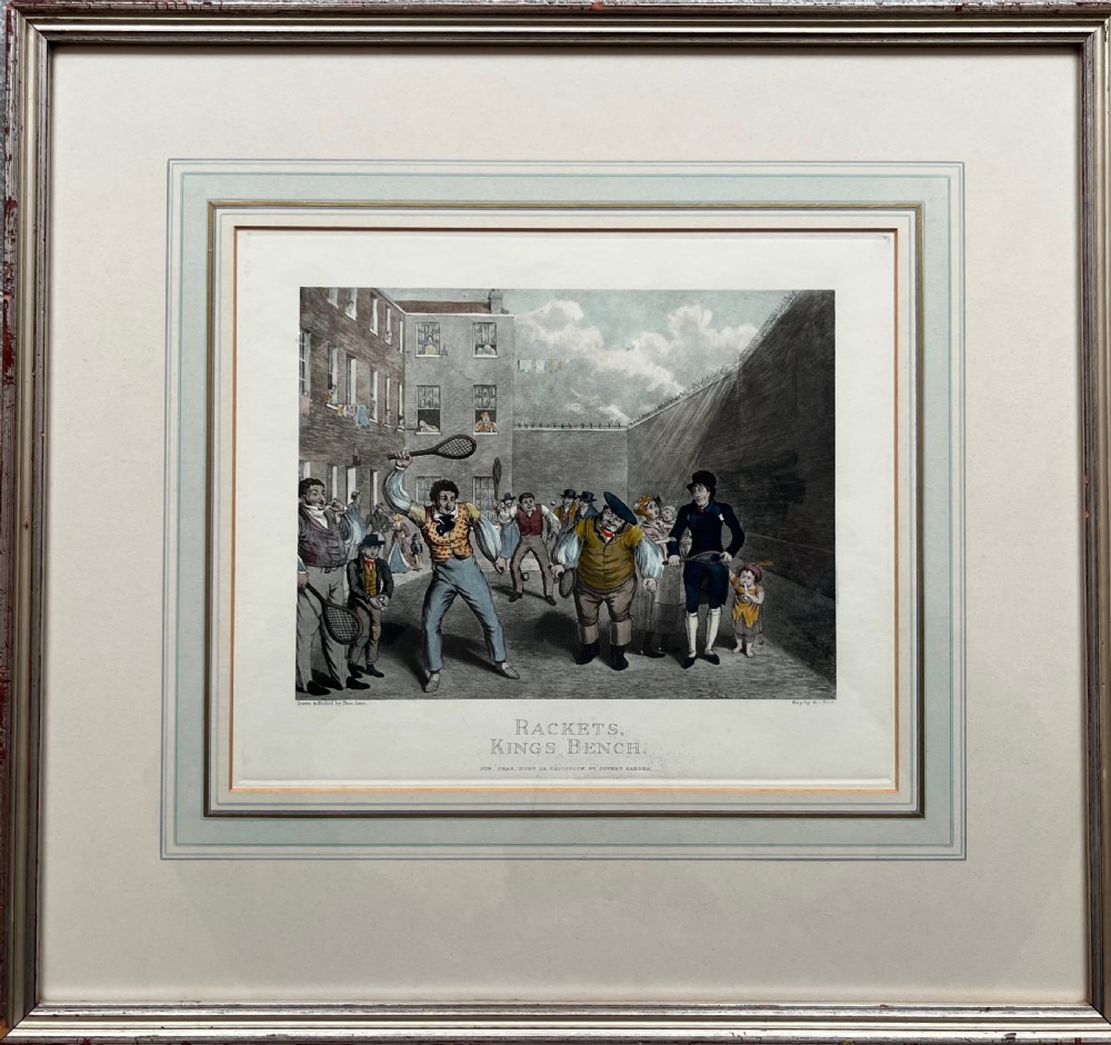 Framed hand-coloured nineteenth-century print depicting figures playing rackets in a prison courtyard.