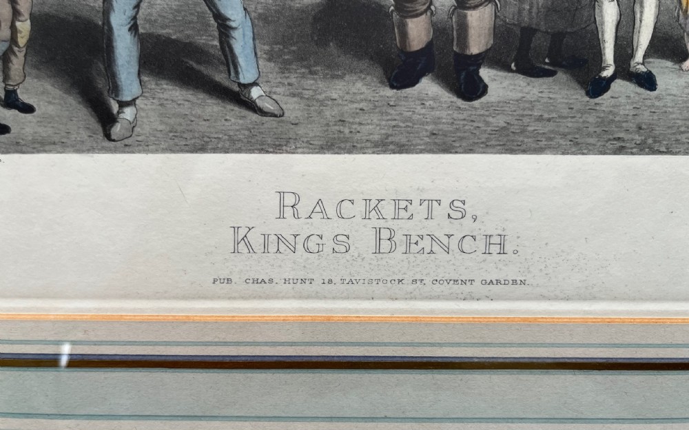 Framed hand-coloured nineteenth-century print depicting figures playing rackets in a prison courtyard. View II