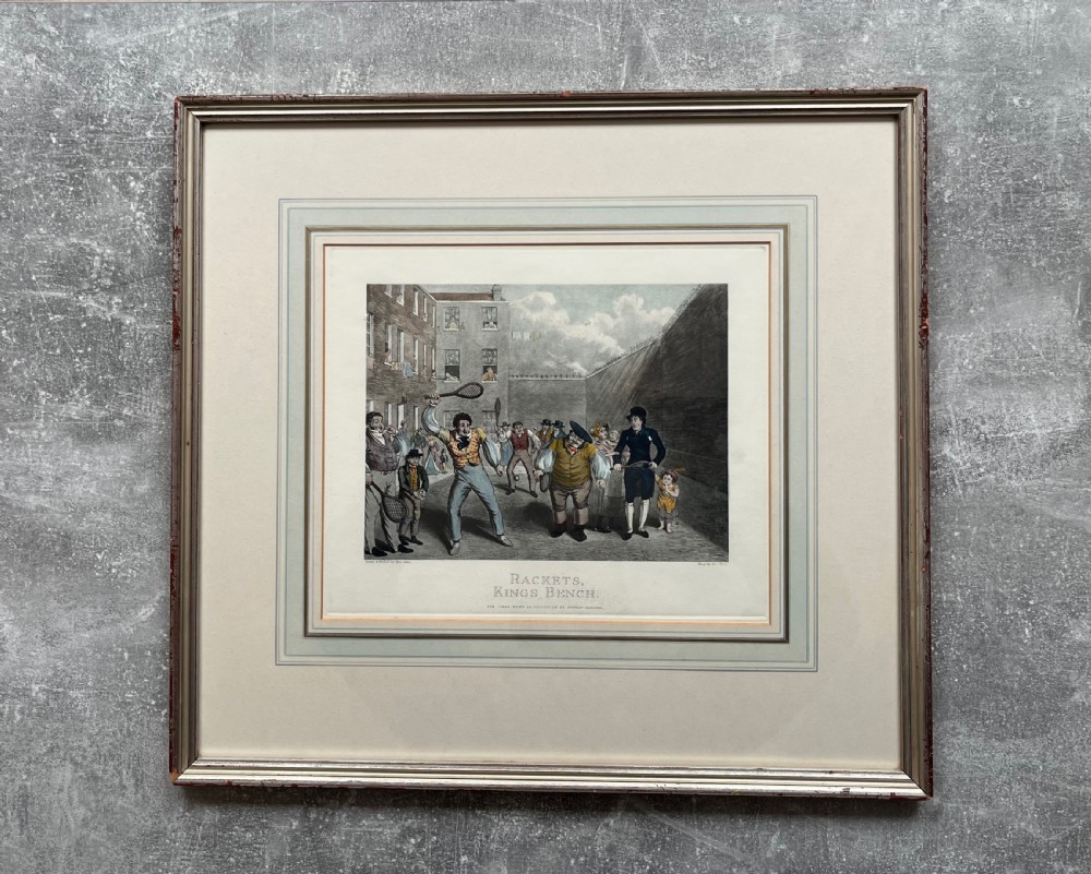 Framed hand-coloured nineteenth-century print depicting figures playing rackets in a prison courtyard. View VI